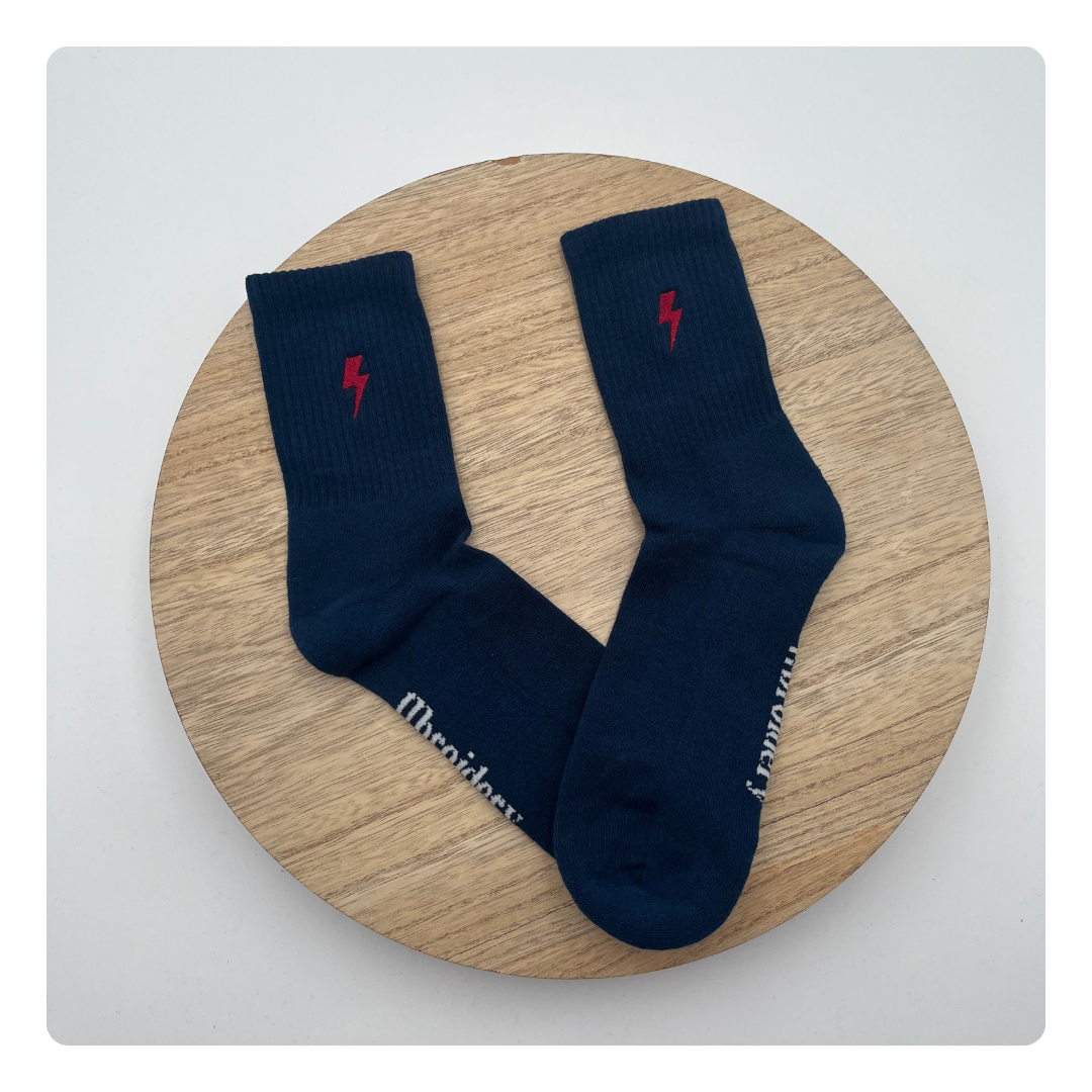 Donkerblauwe sokken met rode bliksemschicht geborduurd – krachtig en opvallend detail
