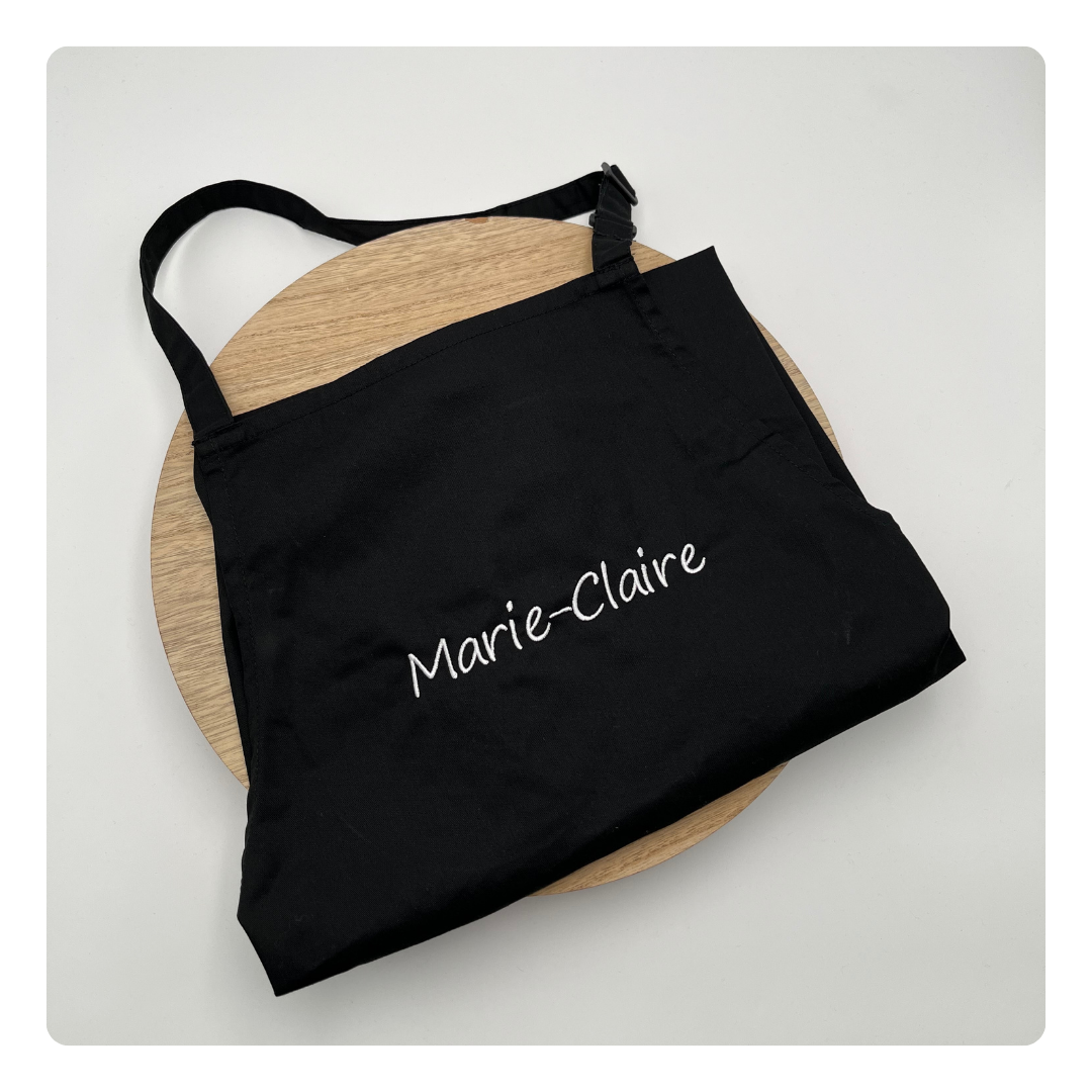 Zwart keukenschort gepersonaliseerd met naam in fijne borduurletters – Mbroidery