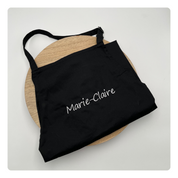 Zwart keukenschort gepersonaliseerd met naam in fijne borduurletters – Mbroidery