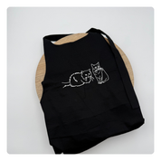 Zwart keukenschort met geborduurde lijntekening van twee katten – subtiel en persoonlijk ontwerp van Mbroidery
